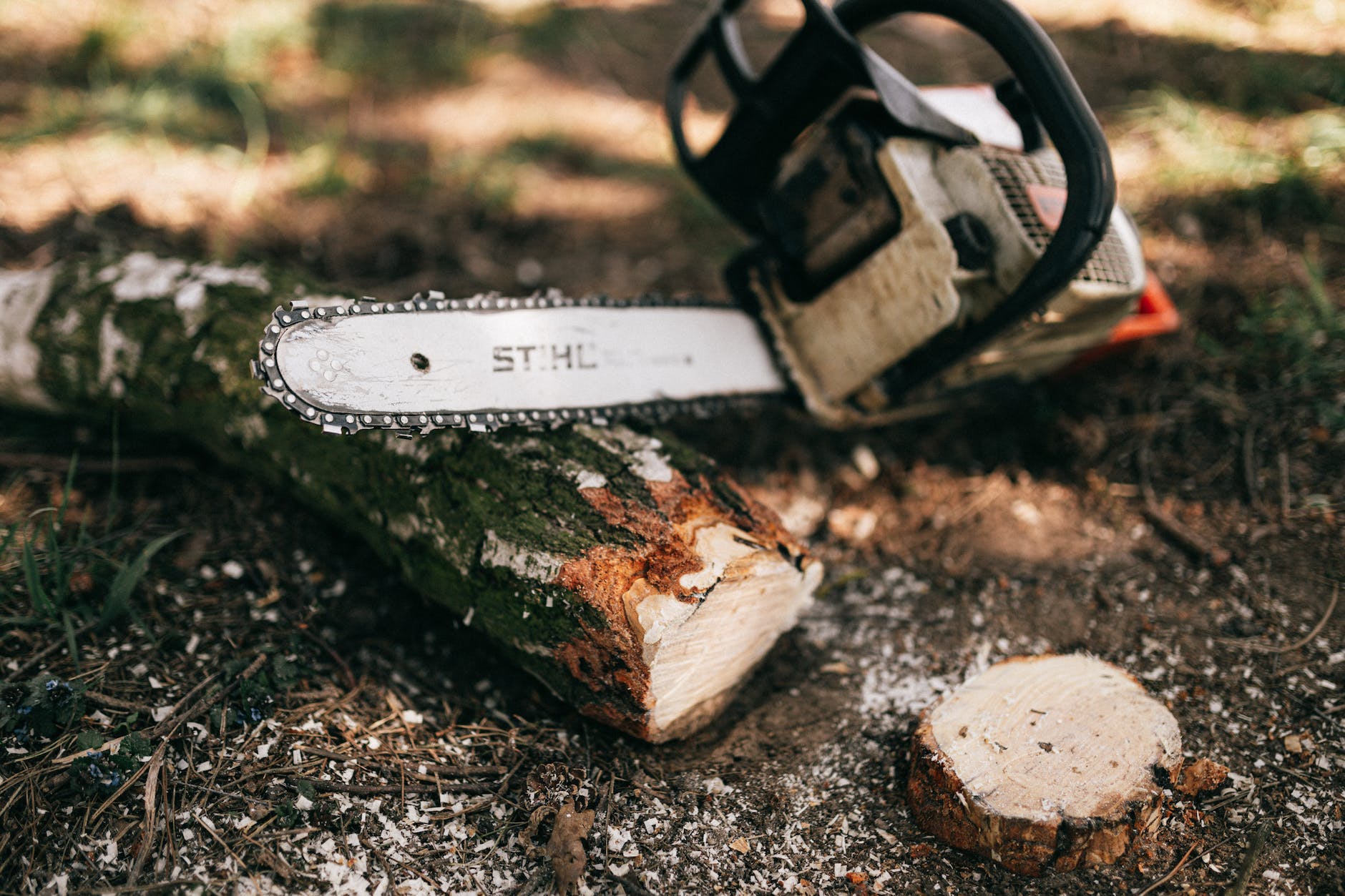 modern gas chainsaw on ground near log